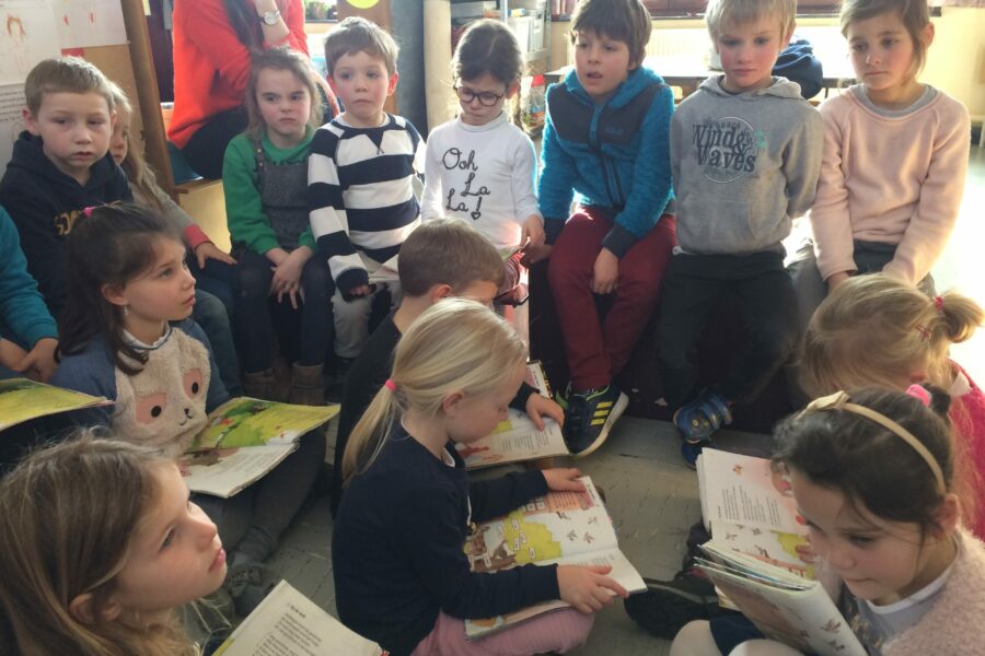 De kinderen van het eerste leerjaar a lezen sprookjes voor in de derde kleuterklas.